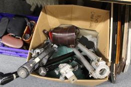 A quantity of camera tripods, monopods, camera lenses and a cine camera.