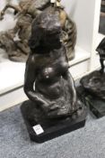 A bronze seated female nude on a marble base.