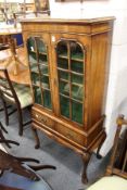 A good small walnut two door display cabinet on stand with two small drawers and carved cabriole