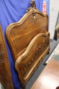 A late 19th century French walnut bedframe with carved decoration.