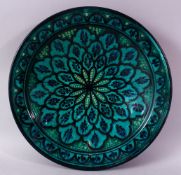 A 20TH CENTURY IZNIK POTTERY CIRCULAR BOWL, green ground painted with flower head design, 39cm
