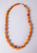 A CHINESE CARVED AMBER AND CORAL BEAD NECKLACE, with graduated oval beads and open measuring 47cm.