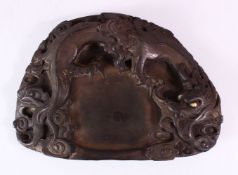 A 19TH CENTURY CHINESE SHAPED INKSTONE, carved with dragons, 23cm x 17cm.