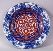 A RARE IZNIK POTTERY PLATE, decorated with blue, white and red decoration depicting stylized