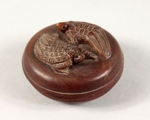 A SMALL JAPANESE CARVED WOOD CIRCULAR BOX, the lid with two turtles. 2.25ins diameter.