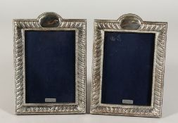A PAIR OF SILVER UPRIGHT PHOTOGRAPH FRAMES with wrythen fluting. 8ins x 5ins.