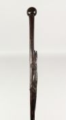 A NATIVE WOODEN WALKING STICK carved with an reptile. 3ft long.