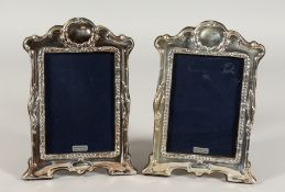 A PAIR OF SILVER UPRIGHT ART NOUVEAU STYLE PHOTOGRAPH FRAMES with serpentine top. 8.5ins x 5ins.