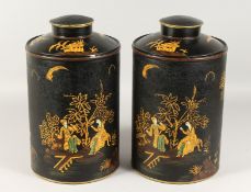 A PAIR OF BLACK TOLEWARE CHINESE DESIGN TEA CANISTERS AND COVERS. 16ins high.