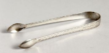 A PAIR OF GEORGIAN BRIGHT CUT SILVER SUGAR TONGS.