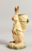 A RARE ROYAL WORCESTER FIGURE OF BR'ER RABBIT carrying a wicker basket on his back, date code 1916.