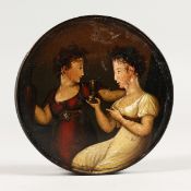 A 19TH CENTURY PAPIER MACHE CIRCULAR BOX, the lid painted with two girls. 3.5ins diameter.