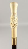 A CARVED BONE HANDLED WALKING CANE, 