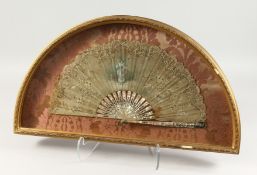 AN 18TH CENTURY FRENCH MOTHER-OF-PEARL AND LACE FAN in a glass case, decorated with a young girl and