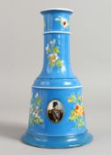 A QAJAR BLUE GROUND BELL SHAPED VASE painted with flowers and oval portraits. 9.25ins high.