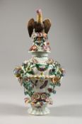 A BOW FLOWER ENCRUSTED PIERCED VASE AND COVER with bird finial, the base with masks, flowers and