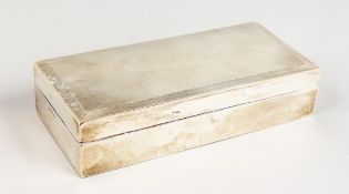 AN ENGINE TURNED SILVER CIGARETTE BOX. 7ins long. Birmingham 1938.