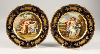 A GOOD PAIR OF 19TH CENTURY PORCELAIN PLATES, rich blue and gilt borders, painted with scenes