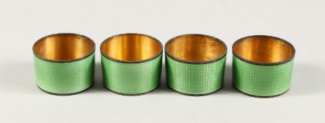 A SET OF FOUR SILVER AND GREEN ENAMEL CIRCULAR VODKA TOTS.