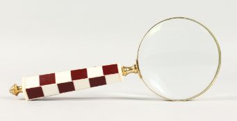 A MAGNIFYING GLASS with chequered handle.