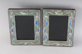 A PAIR OF NOUVEAU SILVER AND ENAMEL PHOTOGRAPH FRAMES. 7.5ins x 6ins.