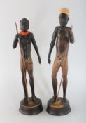 A PAIR OF CARVED WOOD STANDING FIGURES IF A MAN AND WOMAN on circular bases. 9.5ins high.