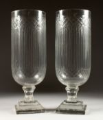 A PAIR OF CUT GLASS STORM LAMPS on square bases. 16ins high.