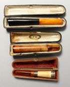THREE CIGARETTE HOLDERS in leather cases.