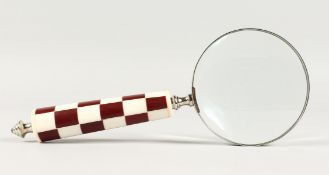 A MAGNIFYING GLASS with chequered handle.