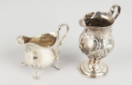 A GEORGE III SILVER HELMET-SHAPED CREAM JUG with repousse decoration, and a small cream jug.