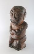 A CARVED WOOD NATIVE FIGURE with arms crossed. 13ins high.