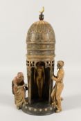 A COLD CAST PAINTED BRONZE of two Arabs and a nude by a tower. 12ins high.