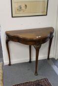 A mahogany shaped top foldover card table on carved cabriole legs.