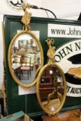 A pair of gilt framed oval mirrors.