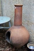 A terracotta chimenea on stand.