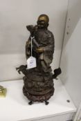 A Chinese bronze figure of a sage mounted on a Chinese hardwood stand.