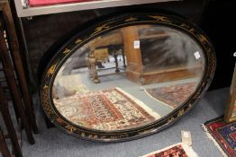 An oval wall mirror with chinoiserie decorated black lacquer frame.