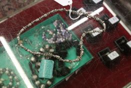 A decorative silver necklace with turquoise drop.