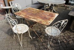 A painted wrought iron rectangular folding table with a set of four wrought iron chairs, two with