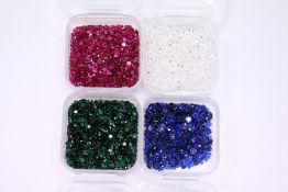 Four small boxes containing small gemstones, comprising rubies, sapphires, emeralds and spinels.