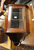 A small mahogany hanging cabinet.