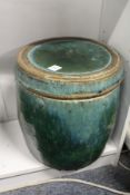 An unusual large green glazed pottery barrel shaped jar and cover, possibly Chinese.