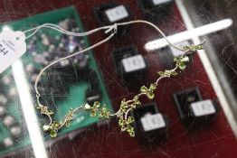 A decorative silver necklace set with peridot style stones.