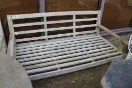 A large hardwood garden settee with loose cushions.