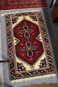 A small Persian rug, red ground with two geometric medalions.