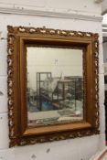 A decoratively framed wall mirror.