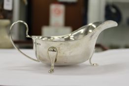 A silver sauce boat on three curving feet.