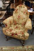 An Elizabethan revival upholstered walnut framed armchair with carved legs united by an X-shaped
