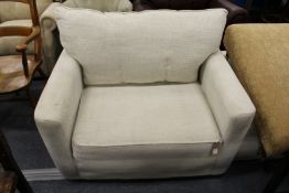 A modern large beige upholstered armchair with matching ottoman foot stool.
