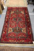 A Persian rug, red ground with stylized bird and tree motifs.